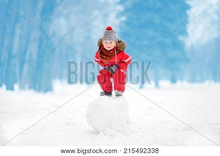 Little Boy In Red Winter Clothes Having Fun With Snowball