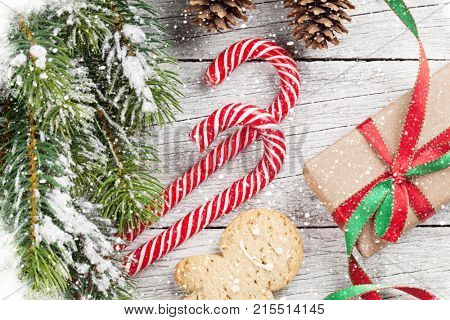Christmas gift box, candy canes and snow fir tree on wooden table. Top view