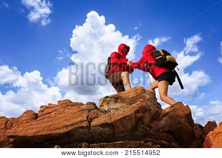 Young asian couple climbing up on the mountain,giving helping hands,support togethers,support,hiking and team work concept.