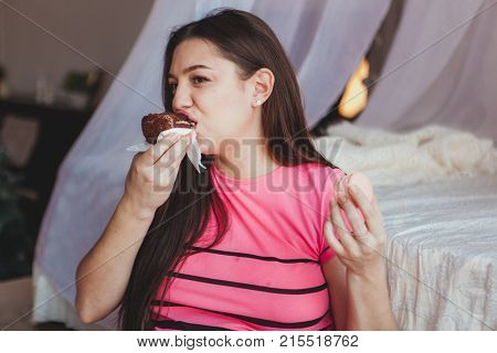 Girl eating tasty browny cake with in bedroom. Sweet dessert. Good morning.