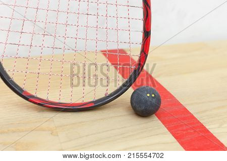 squash racket and ball on the wooden floor. Closeup racquetball equipment on the court near red line. Photo with selective focus