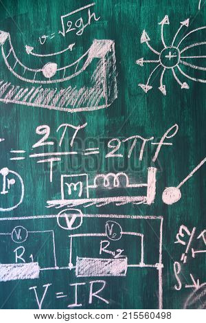 Maths and physic formulas written by white chalk on the blackboard background.
