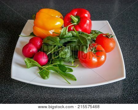 Fresh green vegetable salad with radish tomatoes color peppers on the white plate