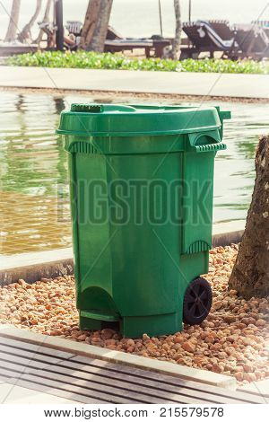 Green Garbage Trash Bin near Swimming Pool extreme closeup.