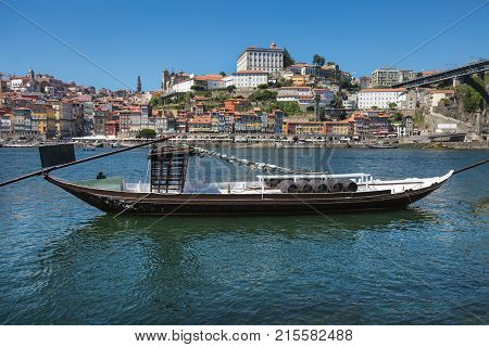 Traditional Rabelo Boat on the Bank of the River Douro and Colorful Facades of Typical Houses- Porto Portugal.