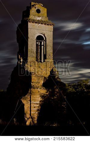 Old ruined bell tower of abandoned church at the moonlit night.
