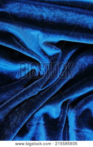 Silk dress material cloth texture pattern. Tailoring stitching concept. Shiny beautiful fashion fabric. Shiny clothing material sample.Creased fabric. Velvet blue.