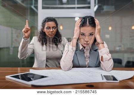 stressed multiethnic businesswomen working with documents in office