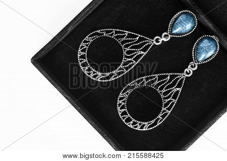 Carved silver earrings with turquoise gems in black jewel box closeup