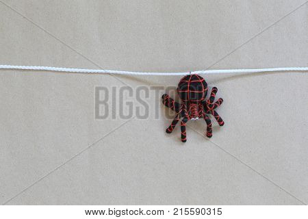 Spider doll hanging on a rope with brown wall background and have copy space for your design in work.