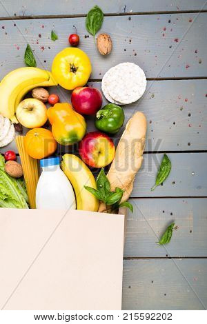 Grocery Shopping Concept. Different Food In Paper Bag On Wooden Background.  Flat Lay.