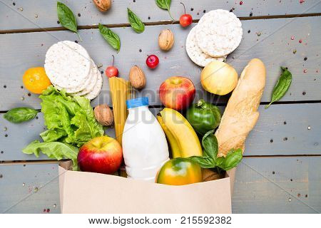 Grocery Shopping Concept. Different Food In Paper Bag On Wooden Background.  Flat Lay.