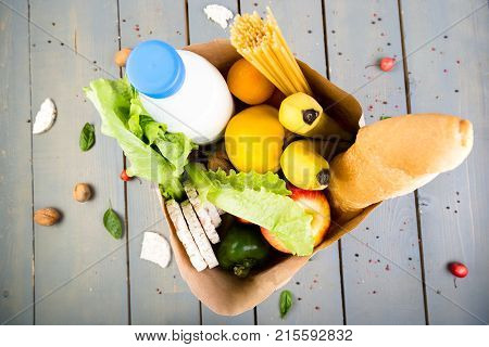 Grocery Shopping Concept. Different Food In Paper Bag On Wooden Background.  Top View.