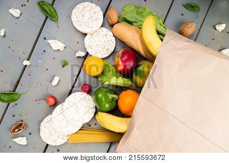 Grocery Shopping Concept. Different Food In Paper Bag On Wooden Background.  Flat Lay.