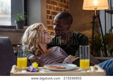 selective focus of interracial couple looking at each other during breakfast at home