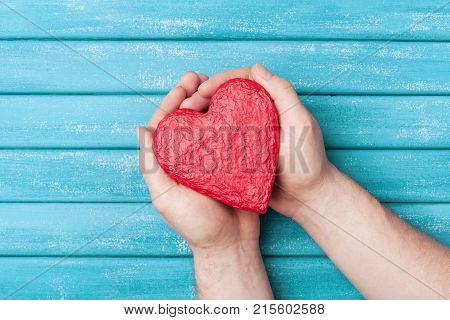 Red heart shape in hands top view. Healthy, donation, organ donor, hope and cardiology concept. Valentines day card.