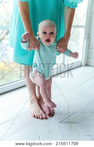 Mother holding her child. Young mother playing whith her daughter. Woman and new born girl relax at home. Mother breast feeding baby. Happy family at home. Young mother playing whith her newborn daughter