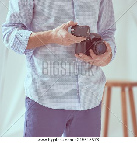 Closeup of young man holding digital camera with synchronizer in studio, focus is on synchronizer, image with vintage toning