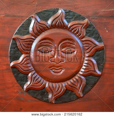 Close up sun with face carved on dark wood used for interior decoration