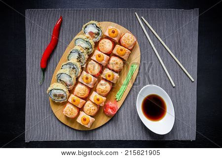 Traditional food. Japanese food - sushi rolls, sauce, pepper and chopsticks on a dack background. Top view. Flat lay