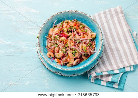 Ecuadorian shrimps ceviche sebiche with tomatoes in blue bowl, wooden blue background. Traditional ecuadorian colombian or mexican dish