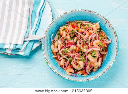 Ecuadorian shrimps ceviche sebiche with tomatoes in blue bowl, wooden blue background. Traditional ecuadorian colombian or mexican dish