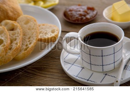 Breakfast with traditional French bread, cup of coffee and butter with jam. Homemade breakfast as perfect start of a new day.
