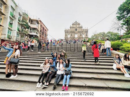 Macao China - March 8 2016: Friends making selfie photos at Ruins of Saint Paul Church in Historical old city center in Macao China. People on the background