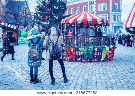 Riga Latvia - December 28 2016: People at carousel in Christmas Market at Dome Square in Riga Old Town in winter