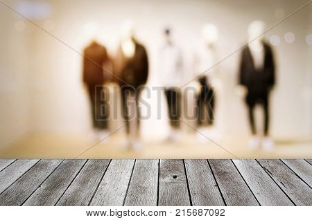 wooden terrace or desk with copy space for display of product or object presentation with blurred image of men fashion clothes shop showcase in department store shopping mall background