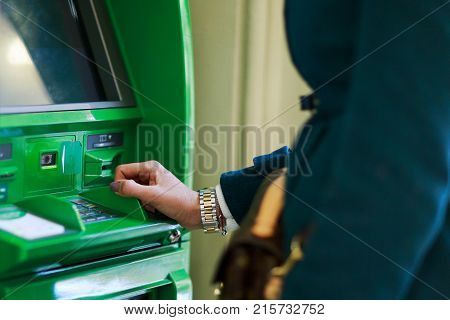Photo of woman in coat at green cash machine in room