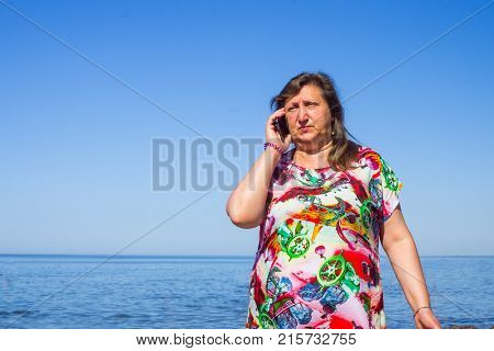 A woman taiking by phone on a beach of a sea