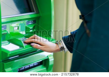 Picture of girl in coat at green cash machine in room