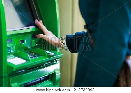 Photo of woman with clock on hand at green cash machine in room