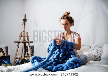 Small business of a young woman. Young woman hand-knitting a wollen blanket.