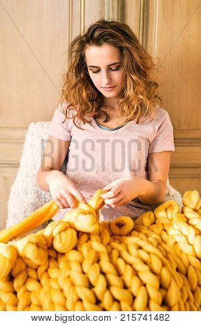 Small business of a young woman. Young woman hand-knitting a wollen blanket.