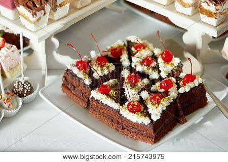 Top view shot of a sliced chocolate cake decorated with whipped cream and cherry on top candy buffet sweets bar dessert sugar eating nutrition hunger celebration party concept.