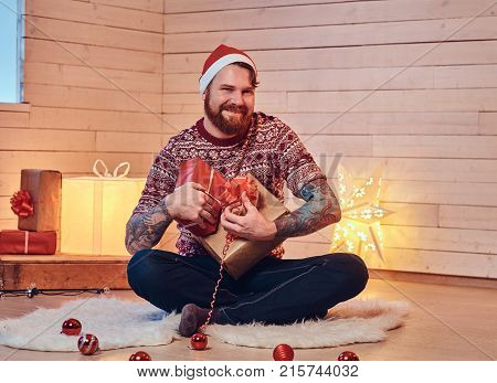 Redhead bearded male in Santa hat in a room with Christmas decoration.