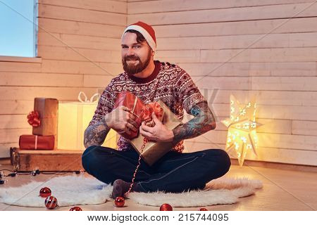 Redhead bearded male in Santa hat in a room with Christmas decoration.