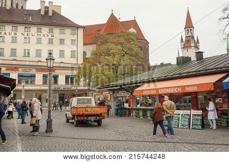 MUNICH, GERMANY - NOVEMBER 16, 2017: People walking in historical city with old buildings small stores and market on November 16, 2017. Bavaria is famous for its breweries and Weissbier -wheat beer