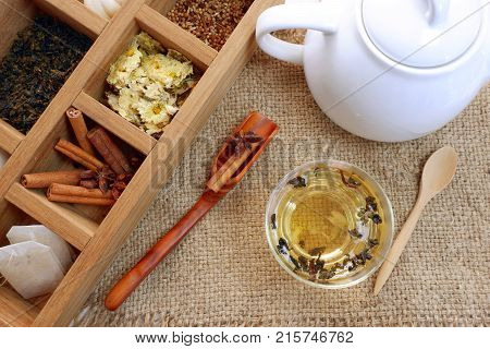 Tea time set,dried tea leaves,dried yellow chrysanthemum flowers ,cinnamon in wooden box and tea pot with China tea with wooden spoon on sack cloth,top view