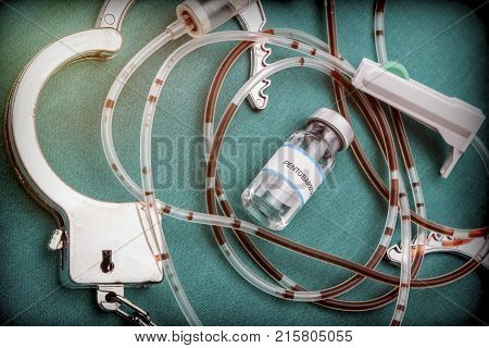 Handcuffs next to a vial of pentobarbital and drip irrigation equipment with traces of blood, concept of capital punishment, conceptual image