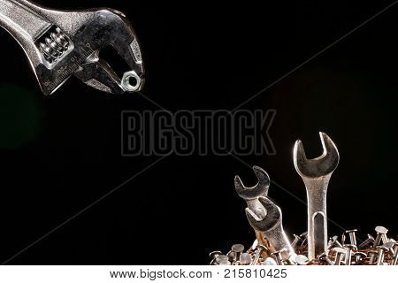 Conception of an adjustable wrench feeding baby wrenches in a nest of nails