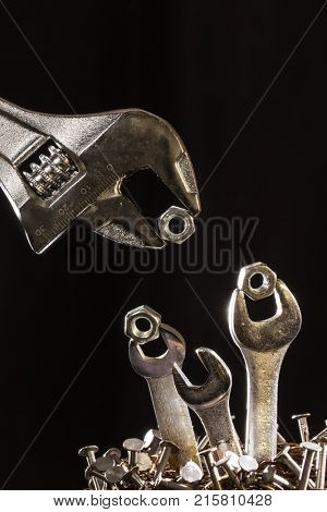 Conception of an adjustable wrench feeding baby wrenches in a nest of nails