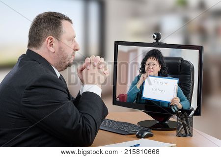 Telemental health patient suffering depression prefers consults psychiatrist from his office. Businessman in black suit sitting at desk attentively looks at virtual doctor on computer monitor