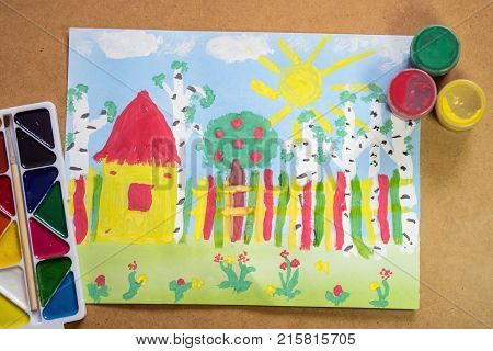 Bright childrens drawing with house fence trees flowers with lying paints - concept of children creativity