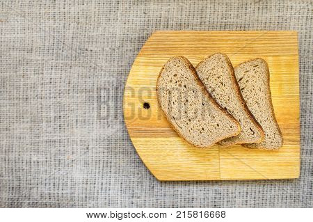 Slice whole wheat bread on wooden yellow board on natural fabric copy space background healthy food concept