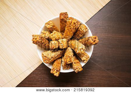 Sunflower seed brittle gosinach kozinaki in a round white plate. Tasty sweets background. Nutritious and delicious healthy snacks. Pressed sunflower seeds candied in sweet syrup.