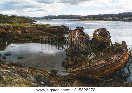 Old destroyed fishing boats in water of the tide near Teriberka
