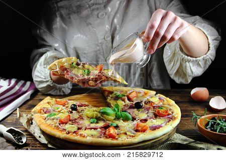 girl eating a pizza with sauce in the kitchen